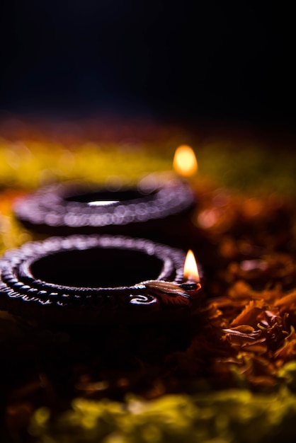 Traditional diya or oil lamp lit on colorful rangoli made up of flower petal, on the festival of lights called diwali or deepawali, selective focus