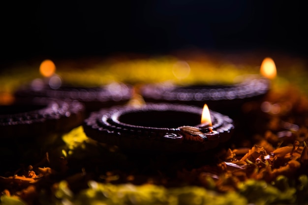 Traditional diya or oil lamp lit on colorful rangoli made up of flower petal, on the festival of lights called diwali or deepawali, selective focus