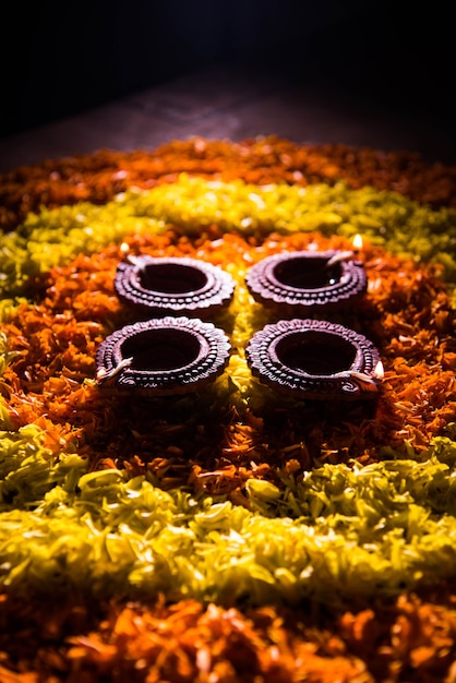 Traditional diya or oil lamp lit on colorful rangoli made up of flower petal, on the festival of lights called diwali or deepawali, selective focus