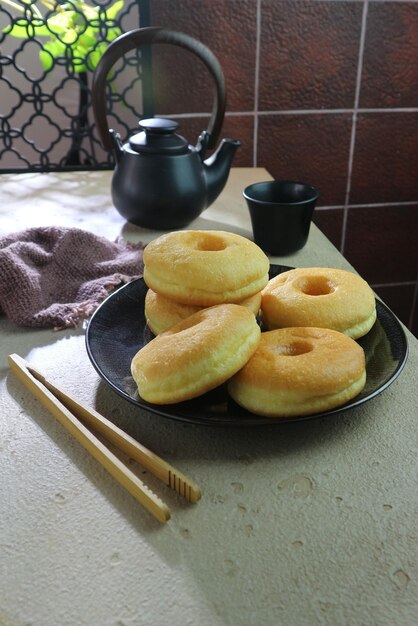 Традиционные пончики, посыпанные сахарной пудрой на фоне чайного сервиза