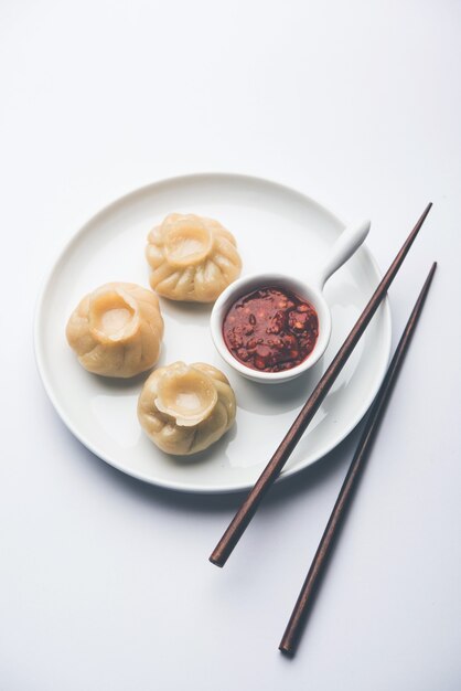 Traditional dumpling momos food from Nepal served with tomato chutney over moody background. Selective focus