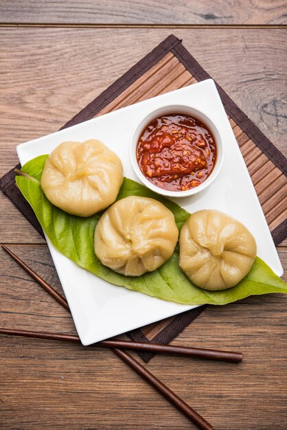 Traditional dumpling momos food from Nepal served with tomato chutney over moody background. Selective focus