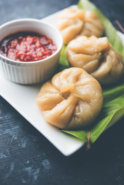 Traditional dumpling momos food from Nepal served with tomato chutney over moody background. Selective focus