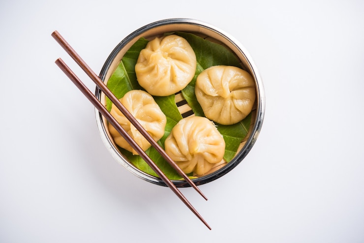 Photo traditional dumpling momos food from nepal served with tomato chutney over moody background. selective focus