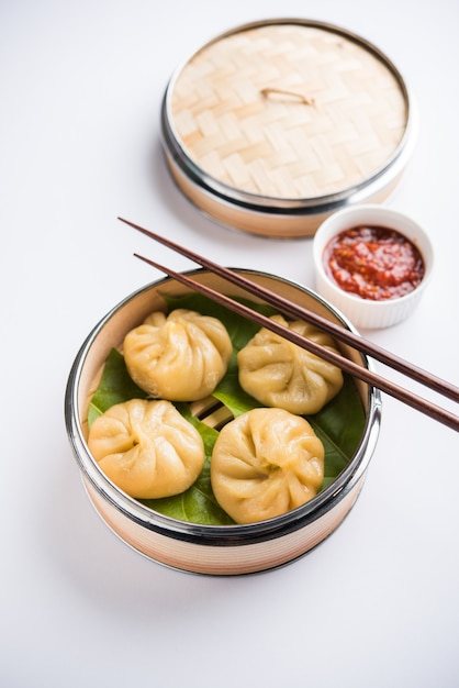 Traditional dumpling momos food from Nepal served with tomato chutney over moody background. Selective focus