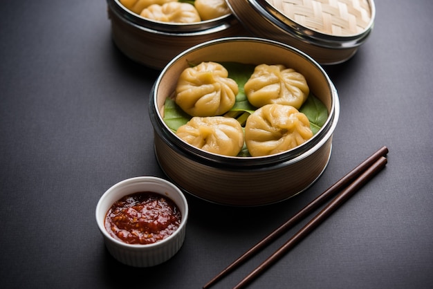 Traditional dumpling momos food from Nepal served with tomato chutney over moody background. Selective focus