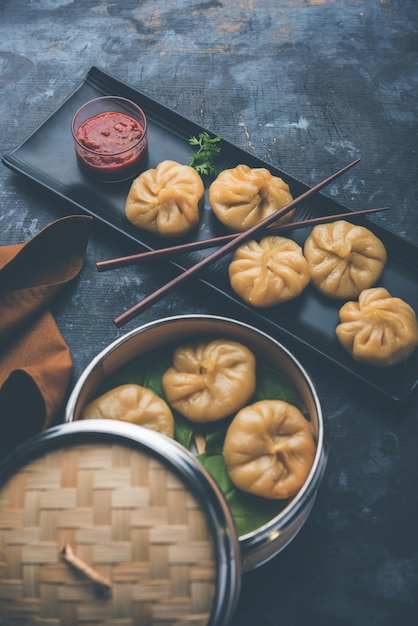 Traditional dumpling momos food from Nepal served with tomato chutney over moody background. Selective focus