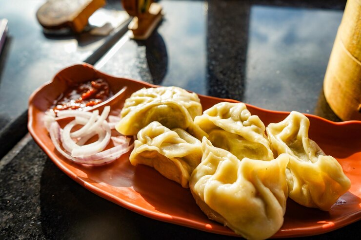 Photo traditional dumpling momos food from nepal served with tomato chutney over moody background