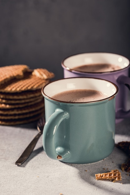 Traditional dutch cookies syrupwaffles over old mug with chocolate milk on gray surface with copy space. Retro style toned