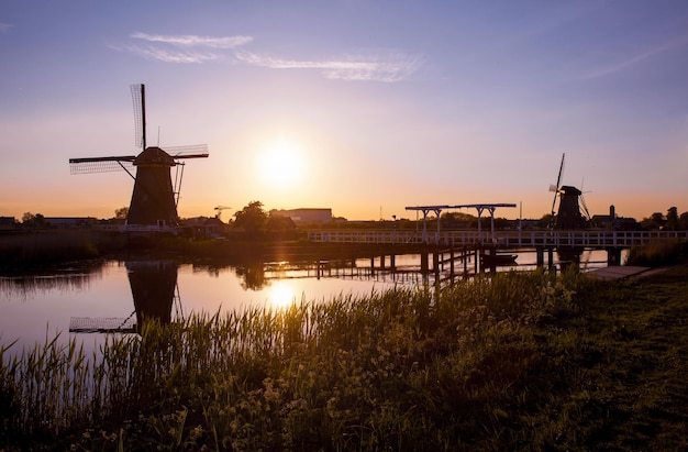 Фото Традиционные голландские ветрянки и деревянный мост, отраженные в водной глади канала