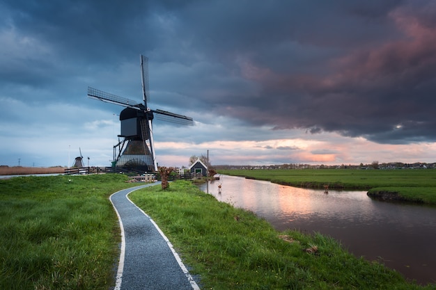 Traditional dutch windmills near water canals with cloudy sky, landscape