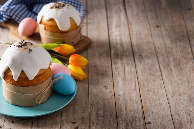 Traditional Easter cake, colorful eggs and tulips on wooden table.