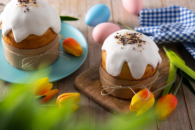 Traditional Easter cake, colorful eggs and tulips on wooden table