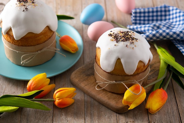 Traditional Easter cake, colorful eggs and tulips on wooden table