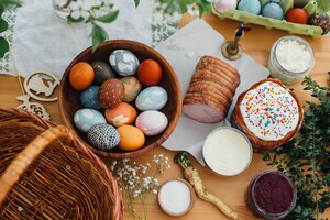 Traditional easter food flat lay easter modern eggs easter bread ham beets butter green branches and flowers on rustic wooden table with wicker basket and candle food for blessing in churchxa