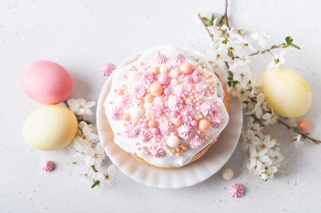 Traditional Easter sweet bread or cakes with white icing and sugar decor colored eggs and cherry blossom tree branch over white table Various Spring Easter cakes Happy Easter day Selective focus