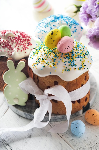 Traditional Easter sweet bread or cakes with white icing and sugar decor and quail eggs over white wooden table Various Spring Easter cakes Happy Easter day Christian traditions Top view