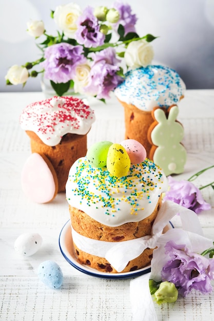 Traditional Easter sweet bread or cakes with white icing and sugar decor and quail eggs over white wooden table Various Spring Easter cakes Happy Easter day Christian traditions Top view