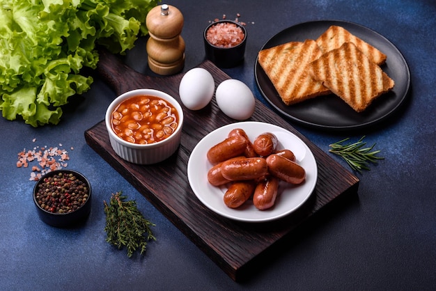 Traditional English breakfast with eggs toast sausages beans spices and herbs on a grey ceramic plate