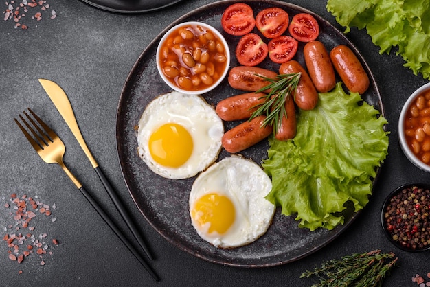 Traditional English breakfast with eggs toast sausages beans spices and herbs on a grey ceramic plate