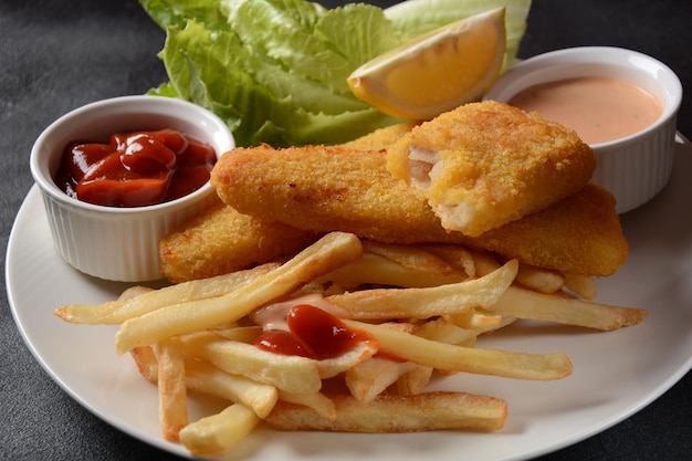 Traditional English Food - Fish and Chips. Fried fish filets and crispy French fries served with ketchup and homemade tarter sauce.