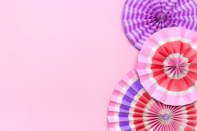 Traditional festival colorful paper fans on pink background with copy space