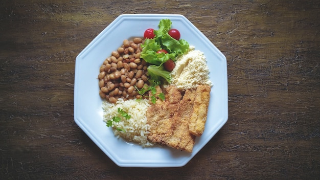 Traditional food dish with fish, beans, rice and salad.