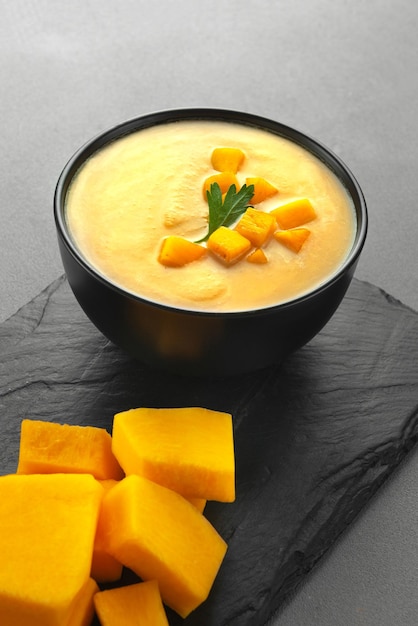 Traditional food on thanksgiving day pumpkin and carrot soup with cream and parsley on dark bowl