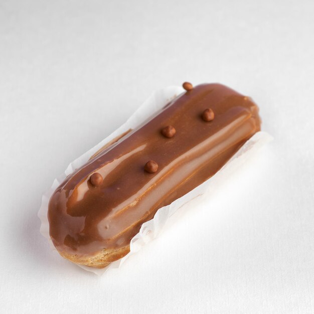 Traditional french dessert eclair with custard and chocolate icing on white background Pastry products for sweet tooth