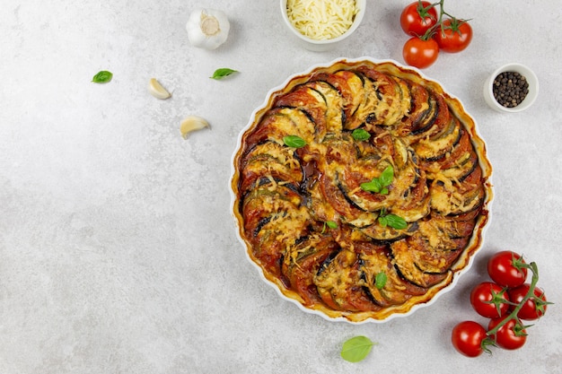 Traditional french dish ratatouille in a white baking dish on a light gray surface