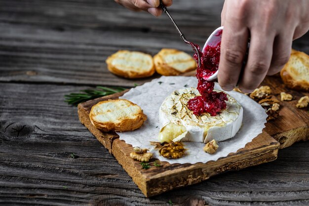 Formaggio camembert cotto in casa tradizionale francese la salsa di mirtilli viene versata sul formaggio da una brocca.