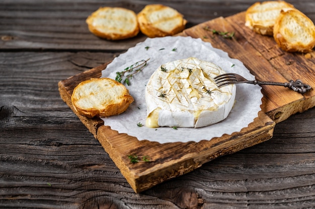 Traditional French homemade baked Camembert cheese with thyme and baguette bread.