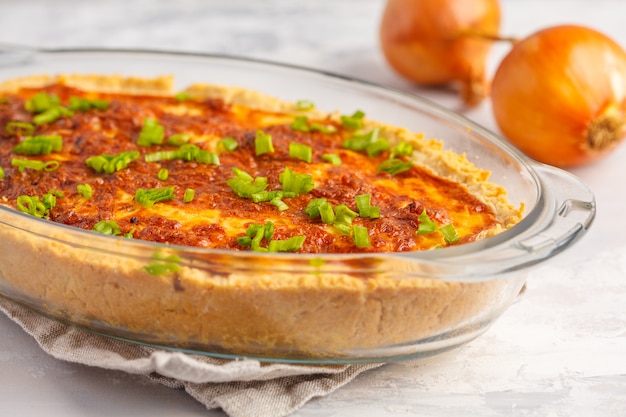 Traditional French onion pie. Quiche lorraine with onion, cheese and eggs in a glass oven dish.
