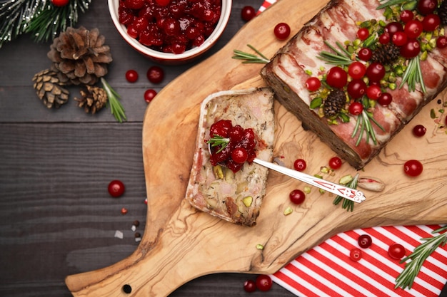 Traditional french terrine covered with bacon on dark wooden background with christmas decorations