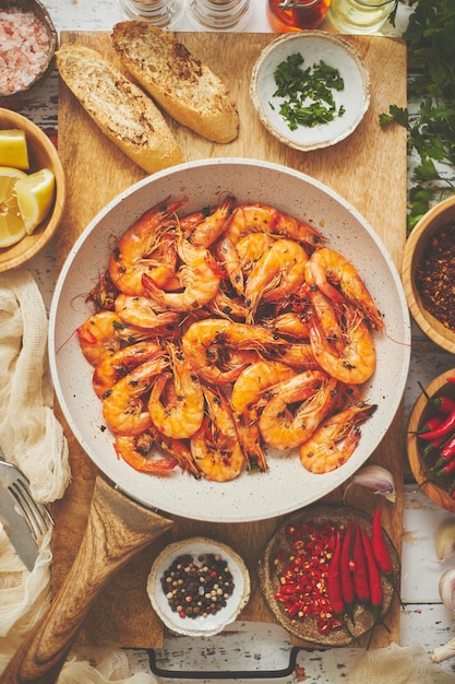 伝統的なフライド・タイガー・スライム (Tiger Shrimp) とガーリック・ブレッド (Garlic Bread) を上から見ると白いフライパン (Frying Pan) で提供され側面に材料が付いている地中海料理コンセプト (Mediterranean food concept) 上から見ると平らなレイ (Flat Lay) 