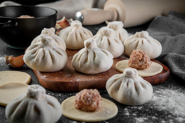 Photo traditional frozen homemade georgian khinkali or manty dumplings ravioli set on a wooden cutting board on a dark table