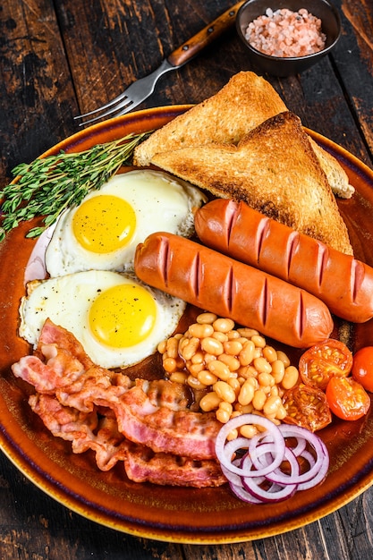 Tradizionale colazione inglese completa con uova fritte, salsicce, pancetta, fagioli e toast