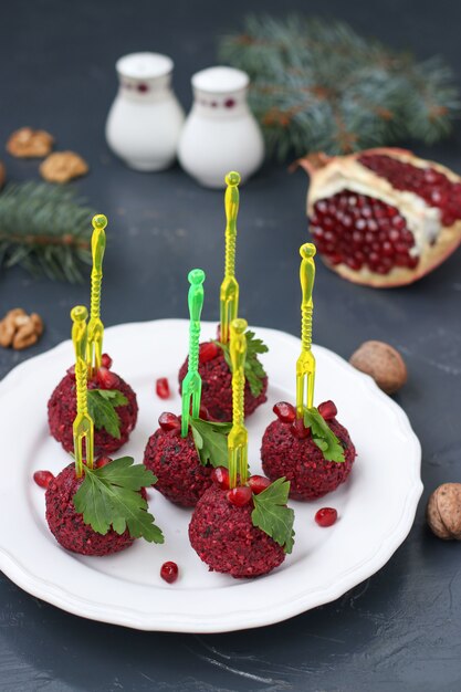 Photo traditional georgian appetizer pkhali from beets, walnuts and pomegranate on a white plate against a dark