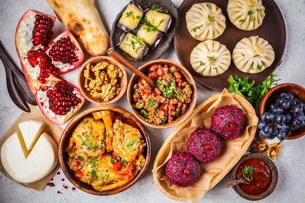 Traditional Georgian cuisine table. Khinkali, phali, chahokhbili, lobio, cheese, eggplant rolls on white table.