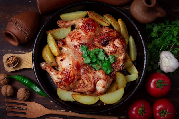 Piatto tradizionale georgiano, pollo al tabacco, con patate, su un tavolo di legno, vista dall'alto.