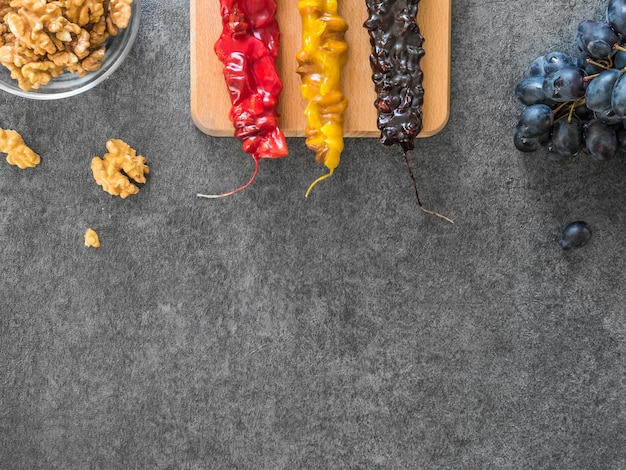 Foto churchkhela dolce casalinga georgiana tradizionale con gli ingredienti su un fondo grigio scuro.