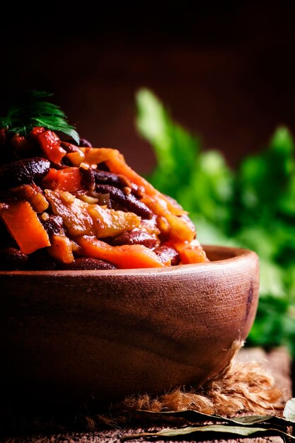 Traditional Georgian lobio from red beans vegetables and tomato on vintage wooden background selective focus