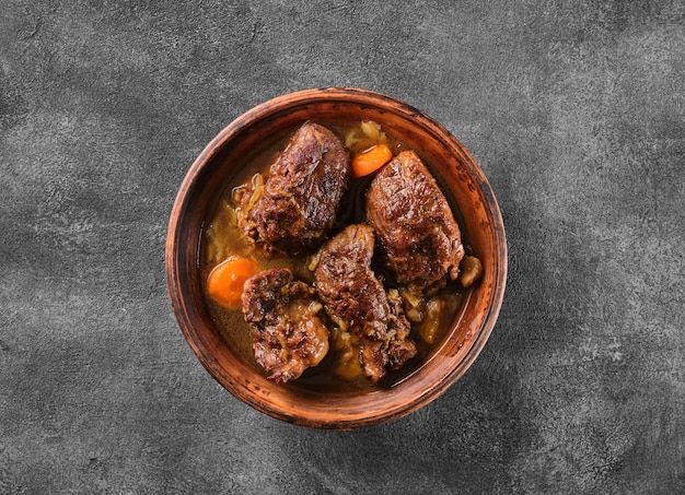 Traditional german braised pork cheeks in brown sauce with\
carrot as closeup