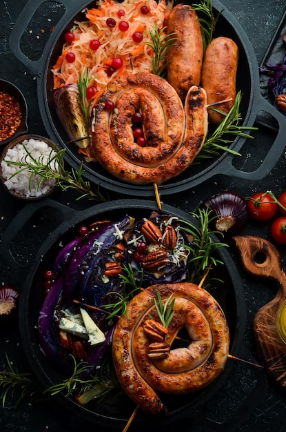 Traditional German dish Grilled sausages cabbage spices and vegetables Top view On a black stone background