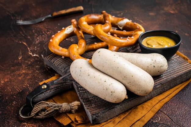 Traditional German pretzel with white sausage and mustard Dark background Top view