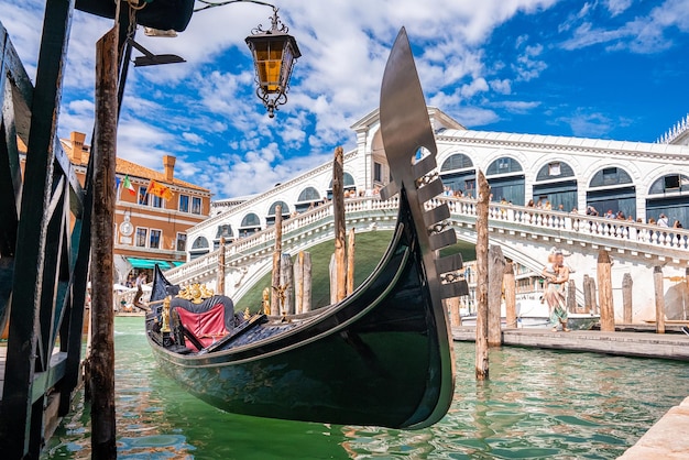Foto tradizionale gondola attraccata al famoso ponte di rialto a venezia, italia. look tradizionale veneziano.