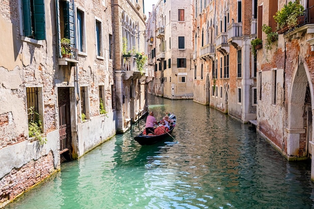 Traditional gondolas on the narrow canal in Venice, Italy. Exploring beautiful Venice on water on a sunny day.