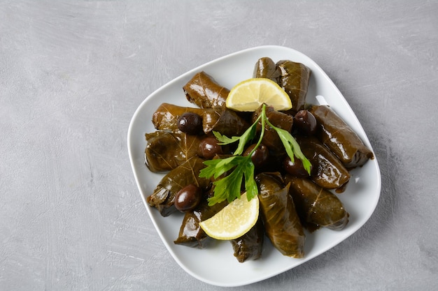 Traditional Greek cuisine. Wrapped rice in grape leaves. Dolma with lemon, spices, various pickled olives and hot peppers.