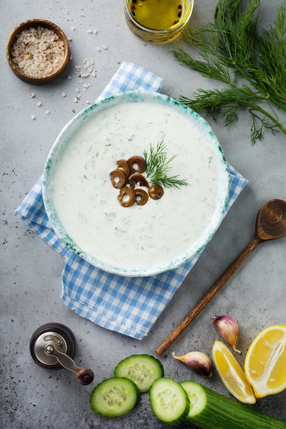 Traditional Greek sauce Tzatziki Yoghurt cucumber dill garlic and salt oil in a ceramic bowl on a gray stone or concrete background Rustic style Selective focus Top view