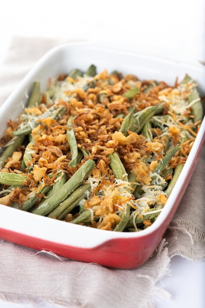 A traditional green bean casserole topped with French Fried Onions and cream of mushroom on white marble Close up